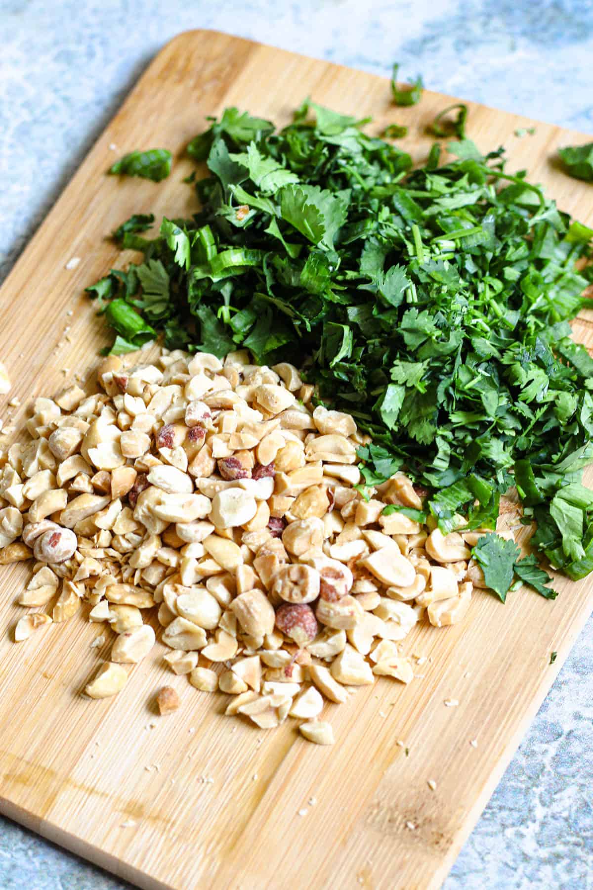 Cutting board with chopped cilantro and peanuts. 