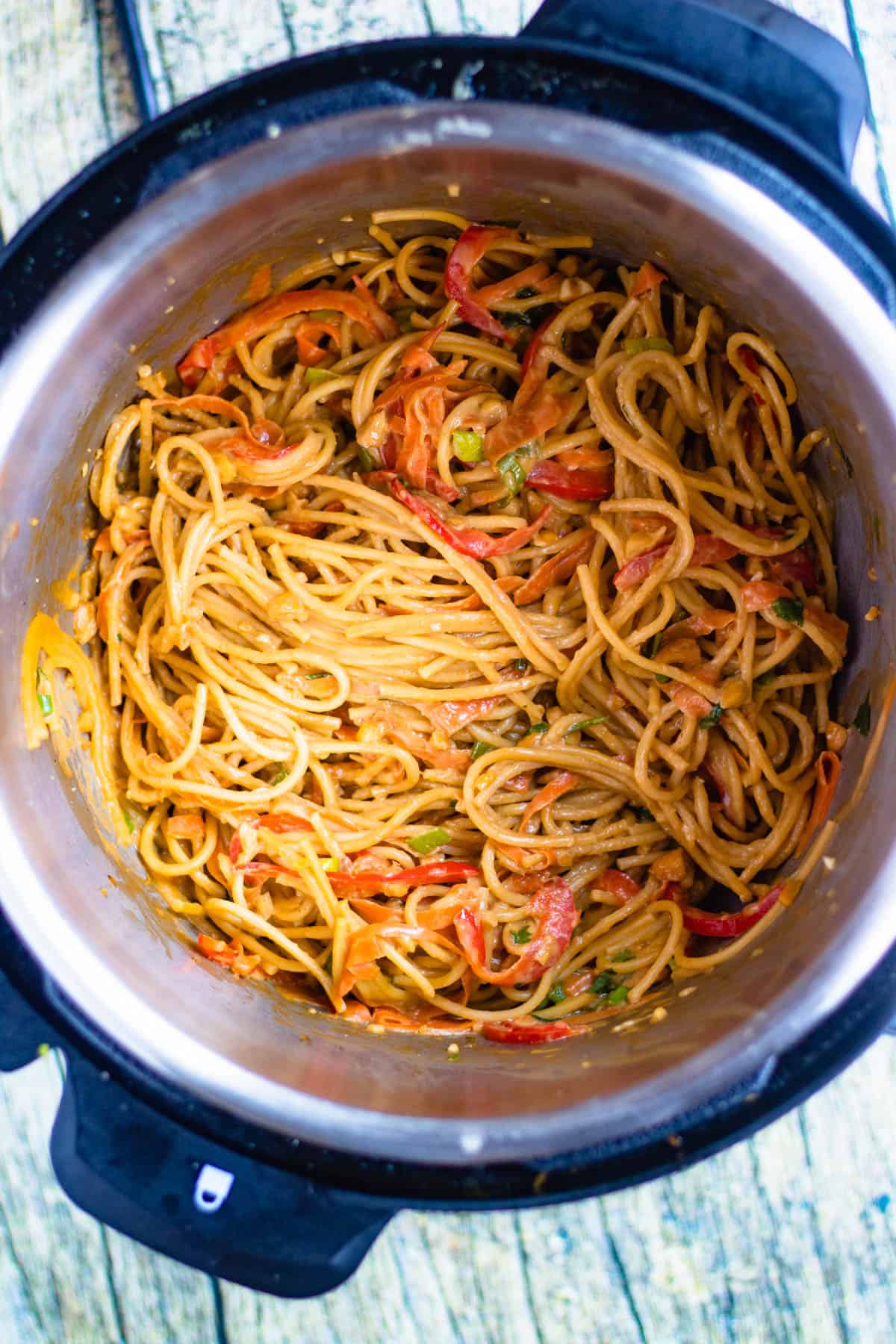 Top view inside Instant Pot with cooked spaghetti noodles and sauteed vegetables added back into the mixture. 