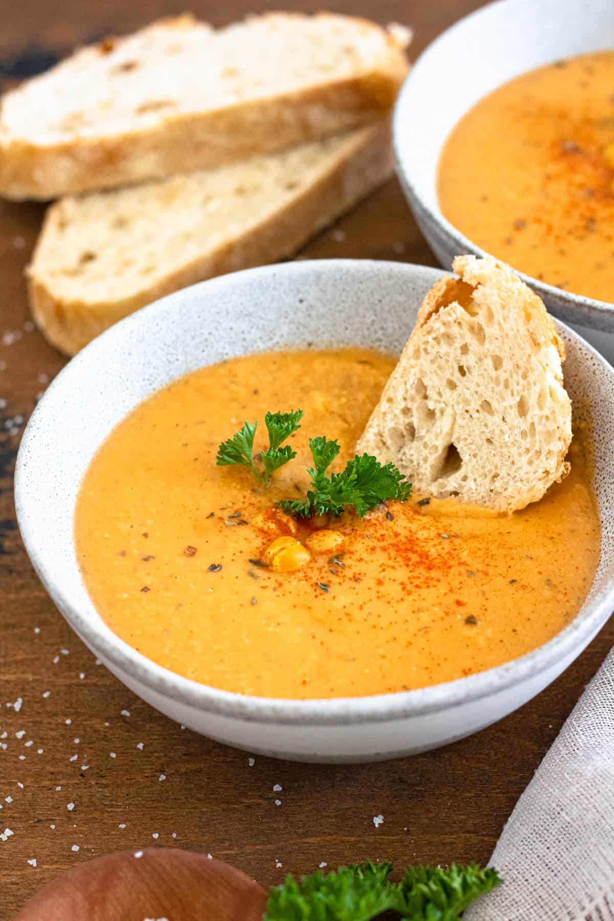Bowl of chickpea soup with a slice of bread tucked in and chickpeas garnished on top. 