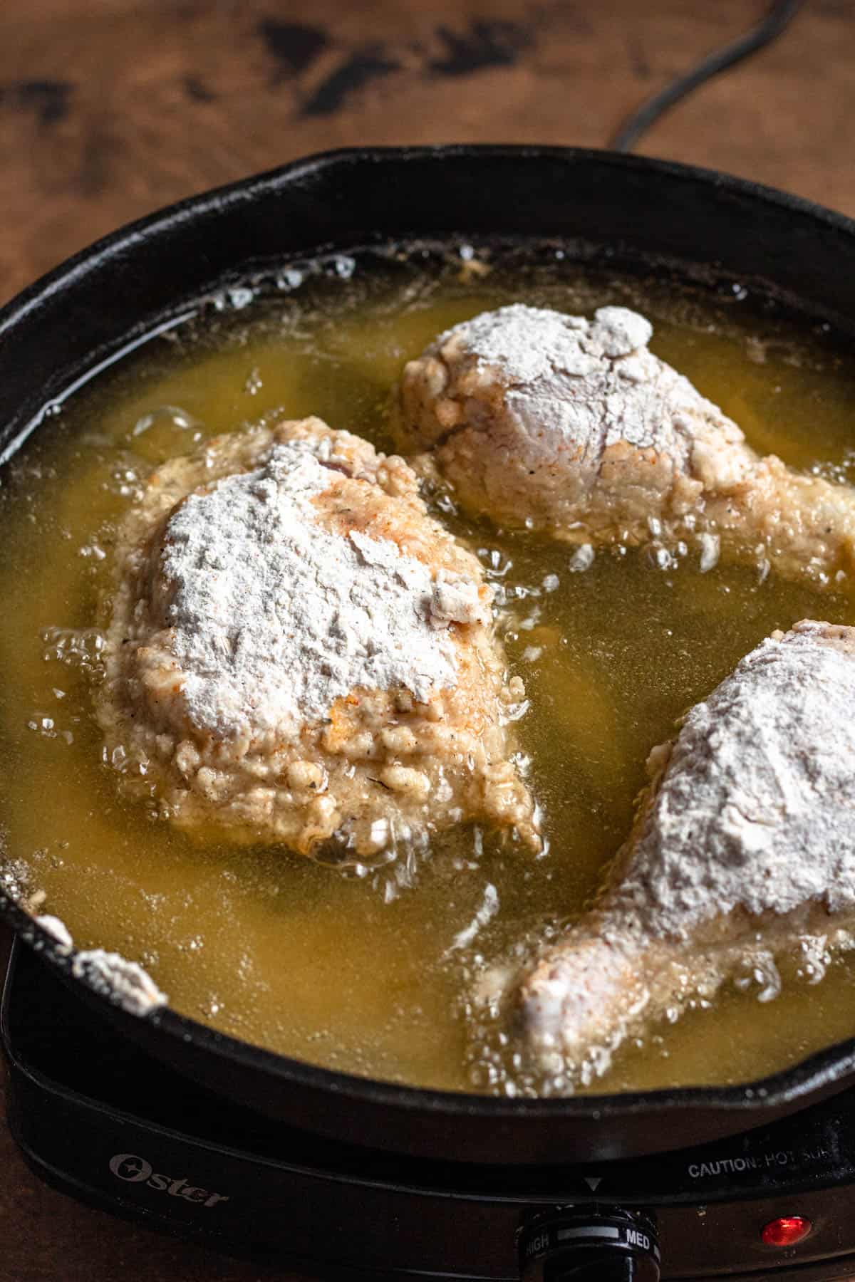 Flour-dredged chicken frying in a batch of oil. 