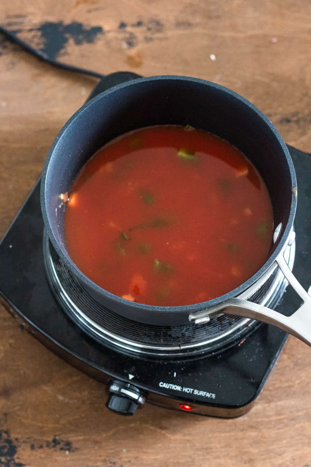 Red tomato sauce cooking in a small pot.