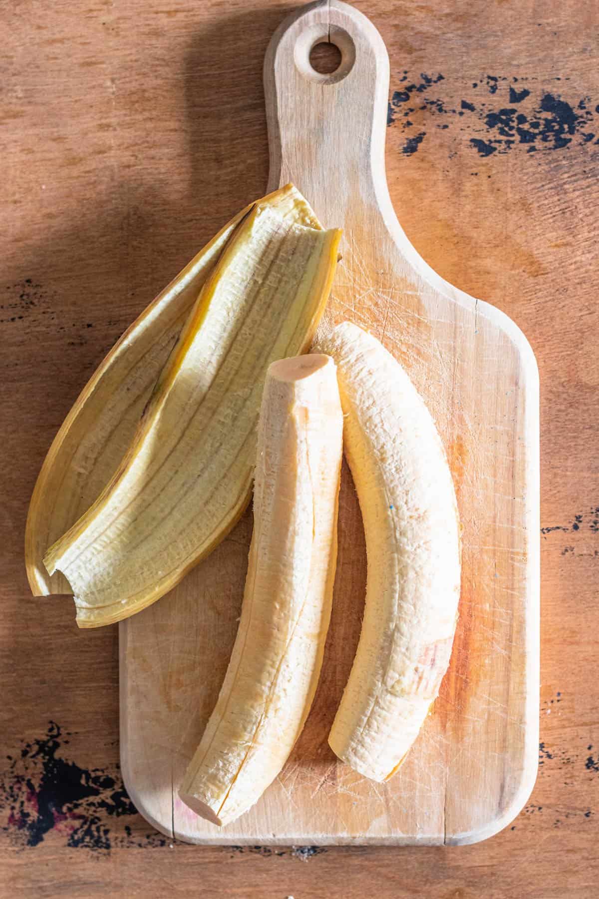 Peeled yellow plantains on a cutting board. 