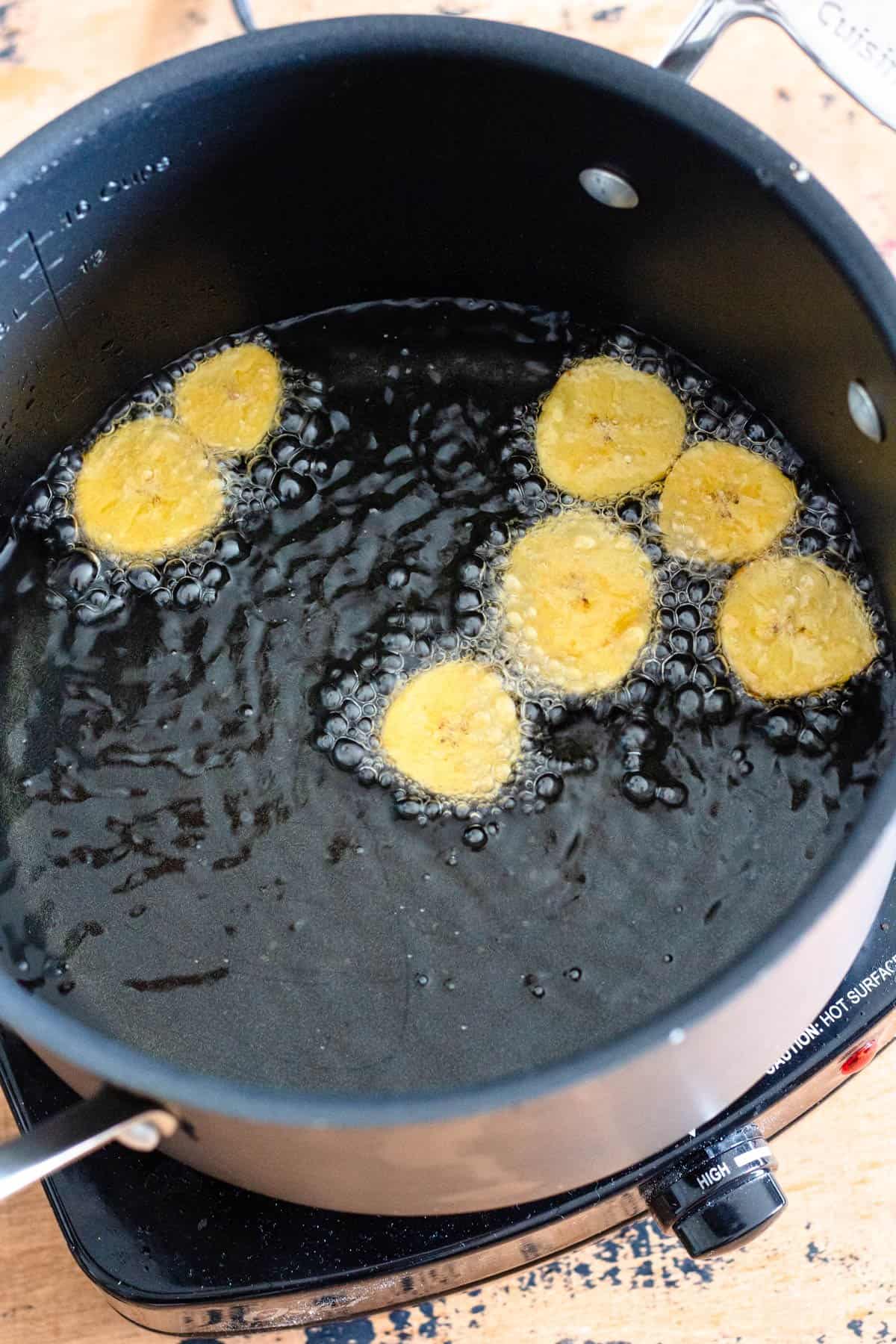 Slices of plantains frying in vegetable oil. 
