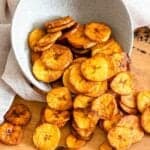 Fried plantain chips spilling out of a serving bowl.
