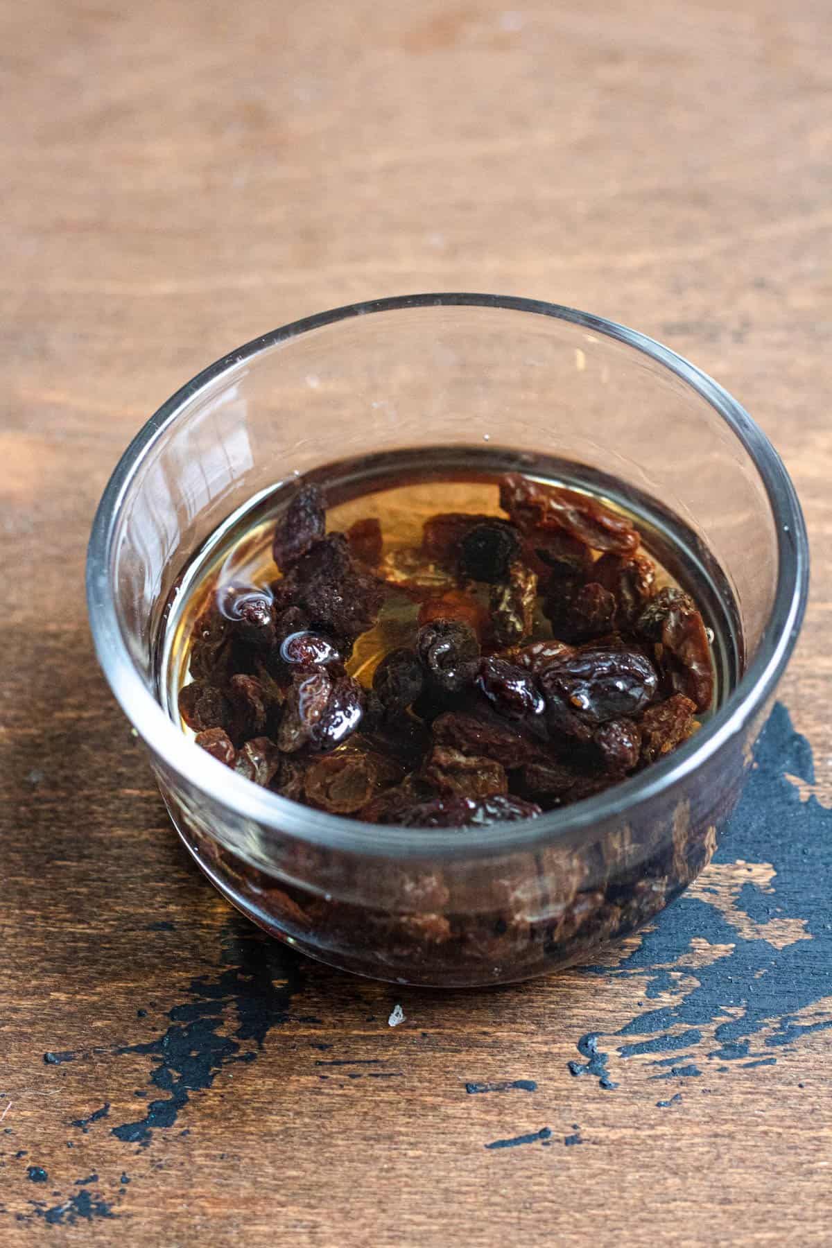 Raisins soaking in rum in a small glass bowl to prepare for Kaiserschmarrn.