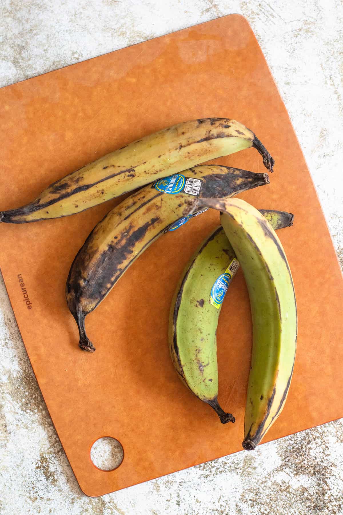 2 ripe plantains and 2 green plantains on a cutting board 