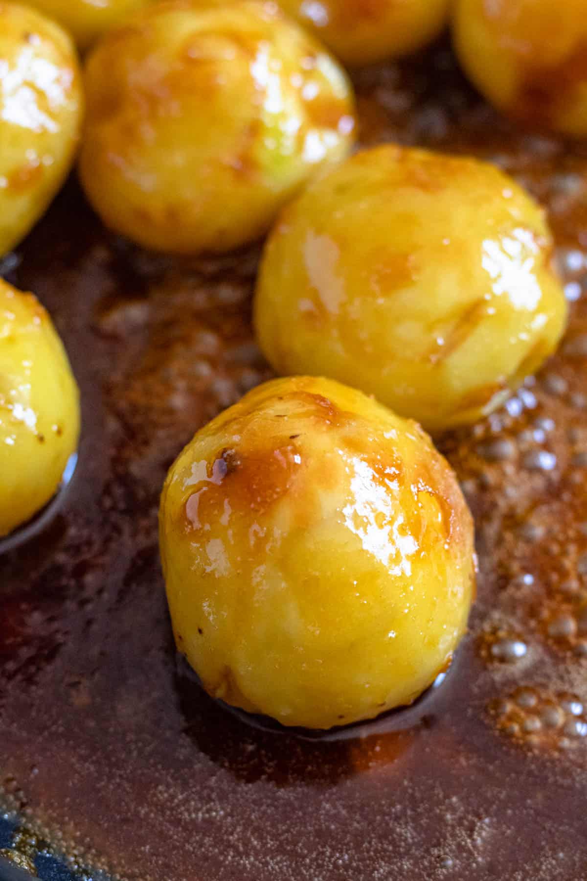 Caramelized potatoes sitting in the sauce shown up close. 