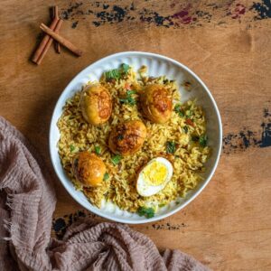 Egg biryani in a white bowl with rice and hard boiled eggs.