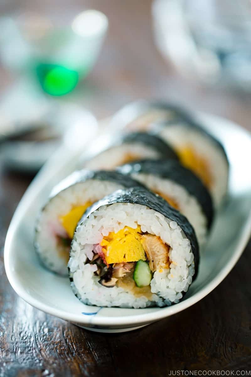 A futomaki roll sliced into bite sized pieces and placed on a rectangular white serving platter. 