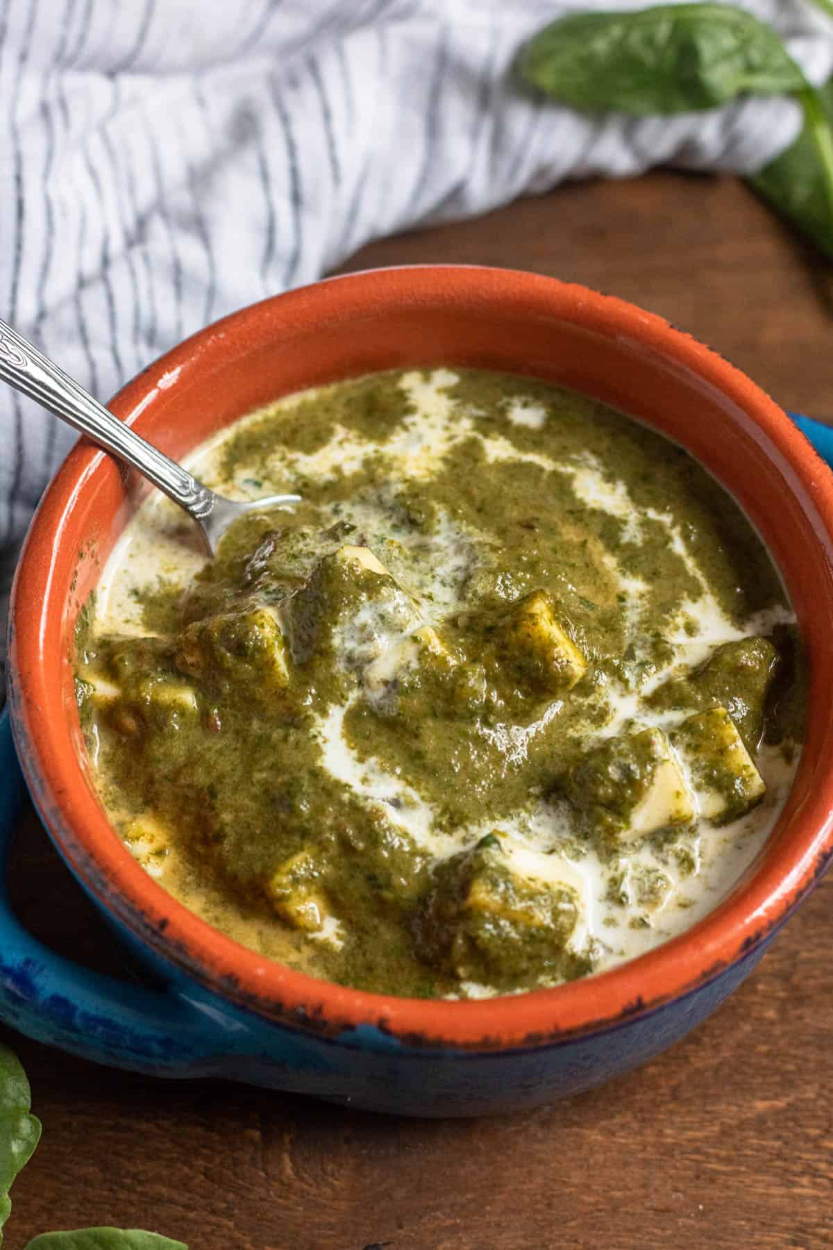 Bowl of Instant Pot Palak Paneer with a spoon tucked in. 