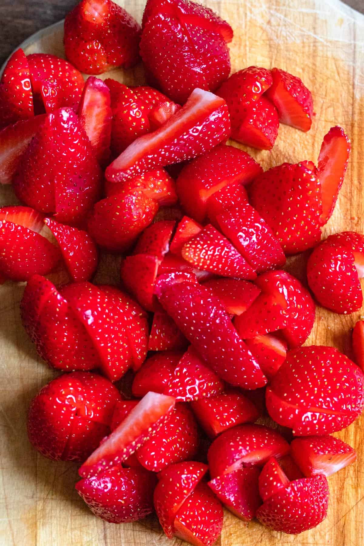 Clean strawberries cut up into pieces on a cutting board. 