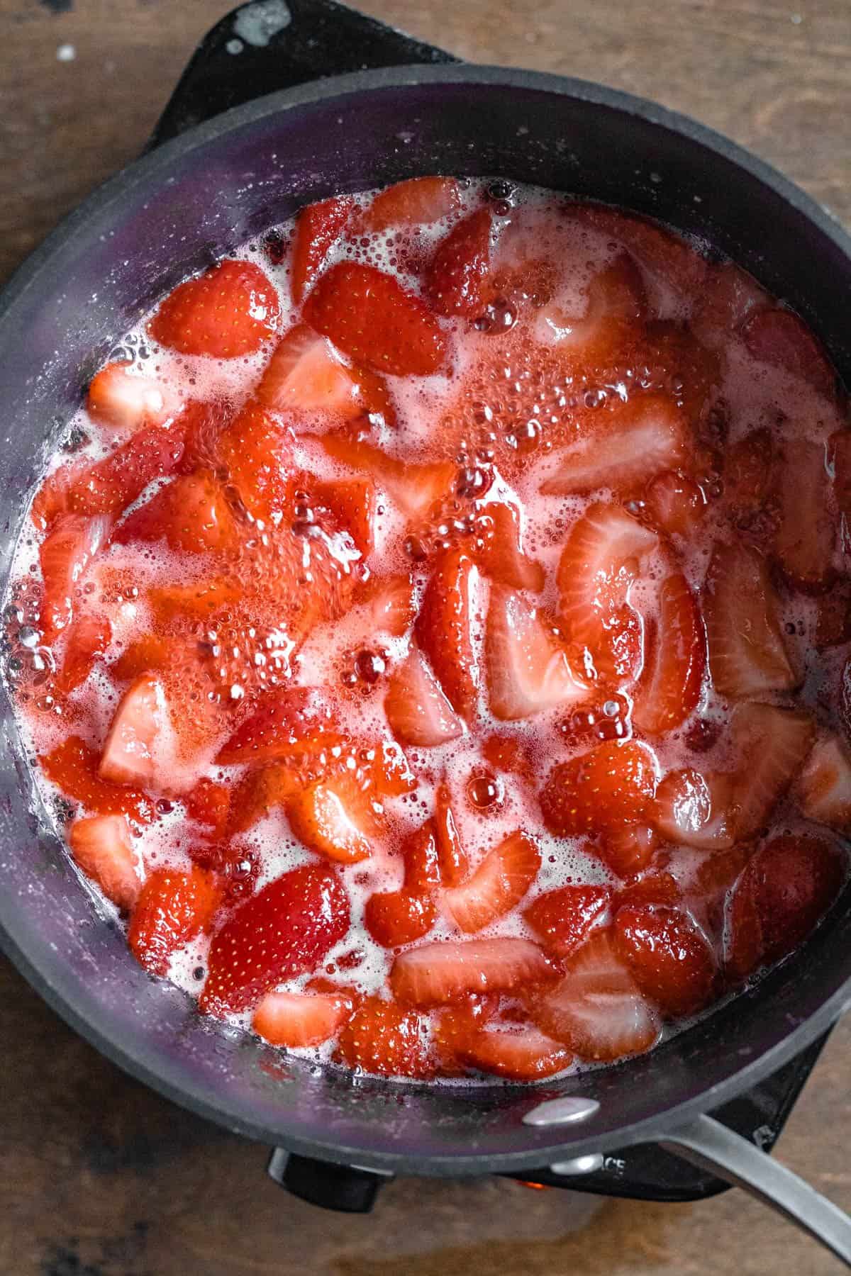 Saucepan with strawberries melting down into a sauce. 