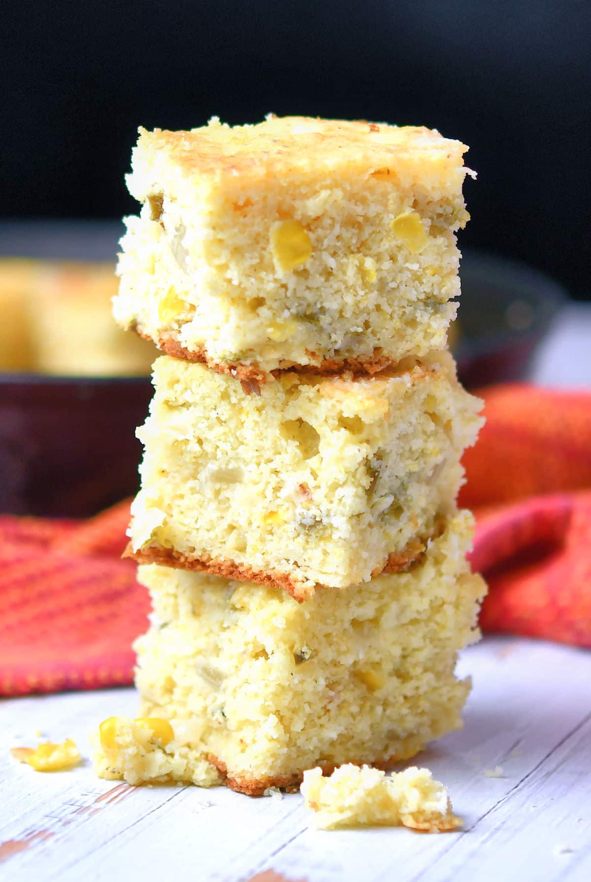 Jalapeno cornbread pieces stacked on top of each other next to a colorful hand towel. 