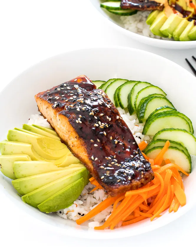 Salmon sushi bowl with rice, avocado, carrots, cucumbers, salmon, and sesame seeds. 