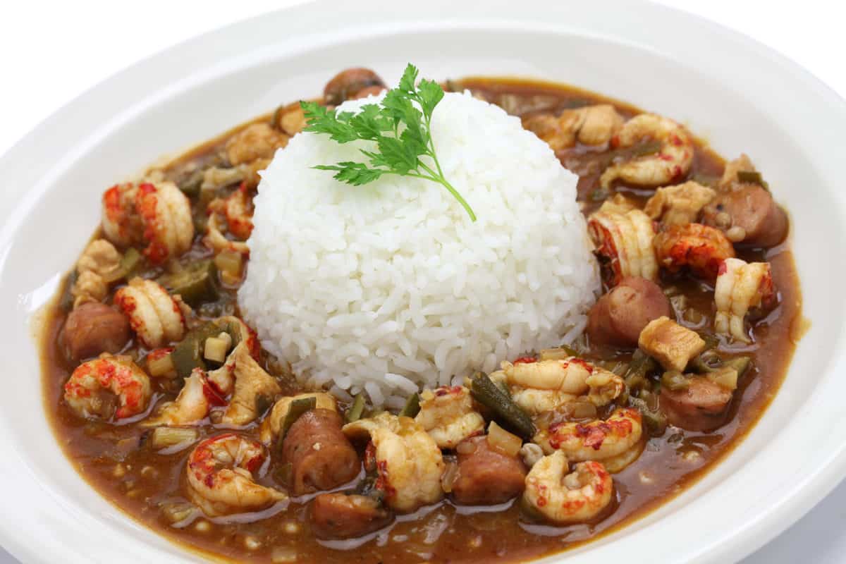 Bowl of gumbo served with a small serving rice in the middle of the gumbo. 