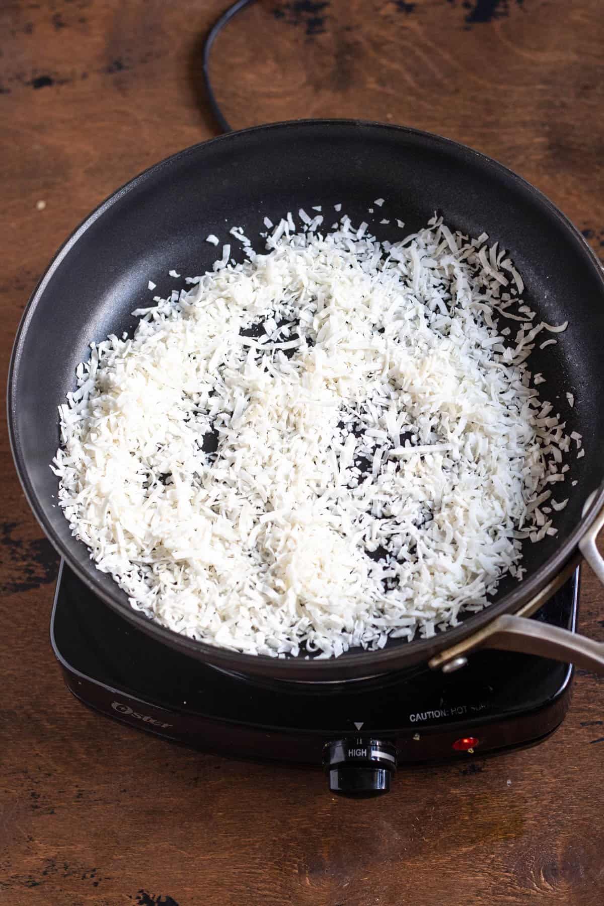 Coconut added to a frying pan. 