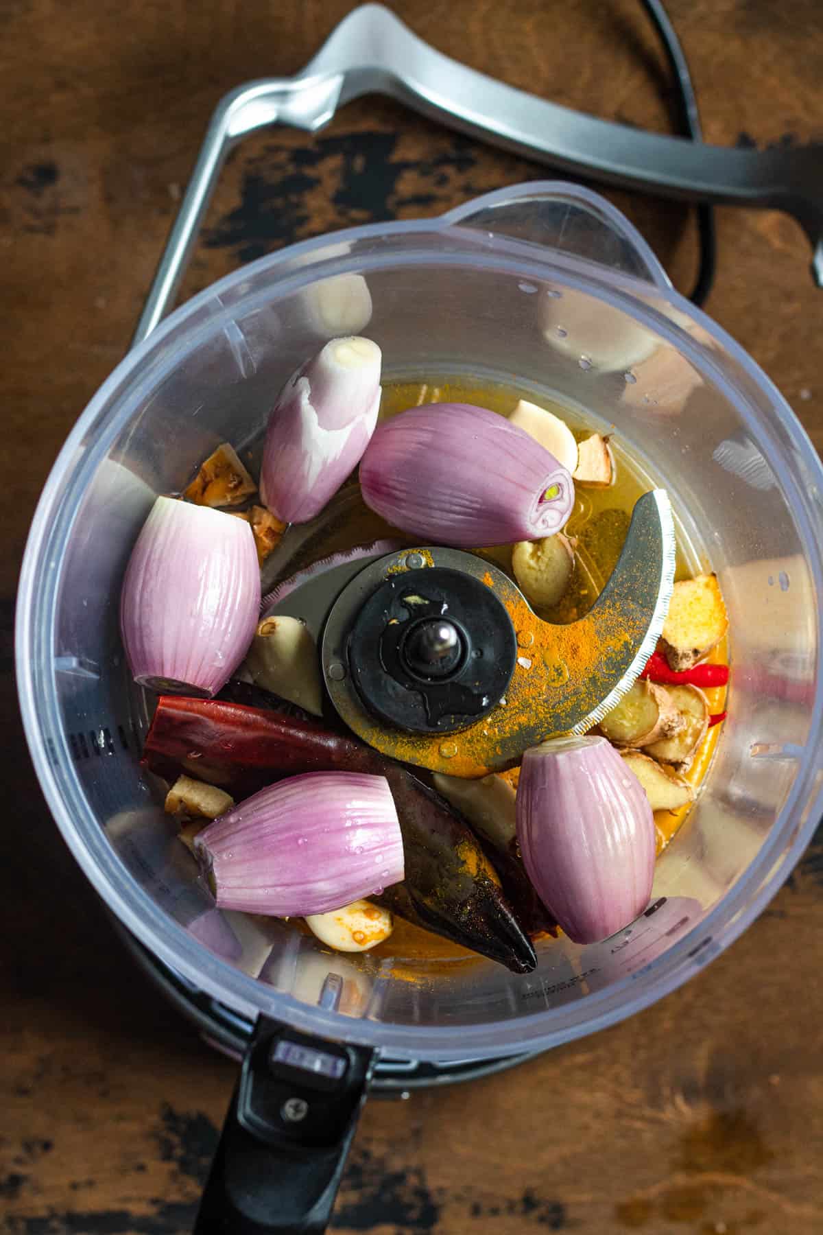 Shallot, chilies, ginger, and other ingredients in a food processor. 
