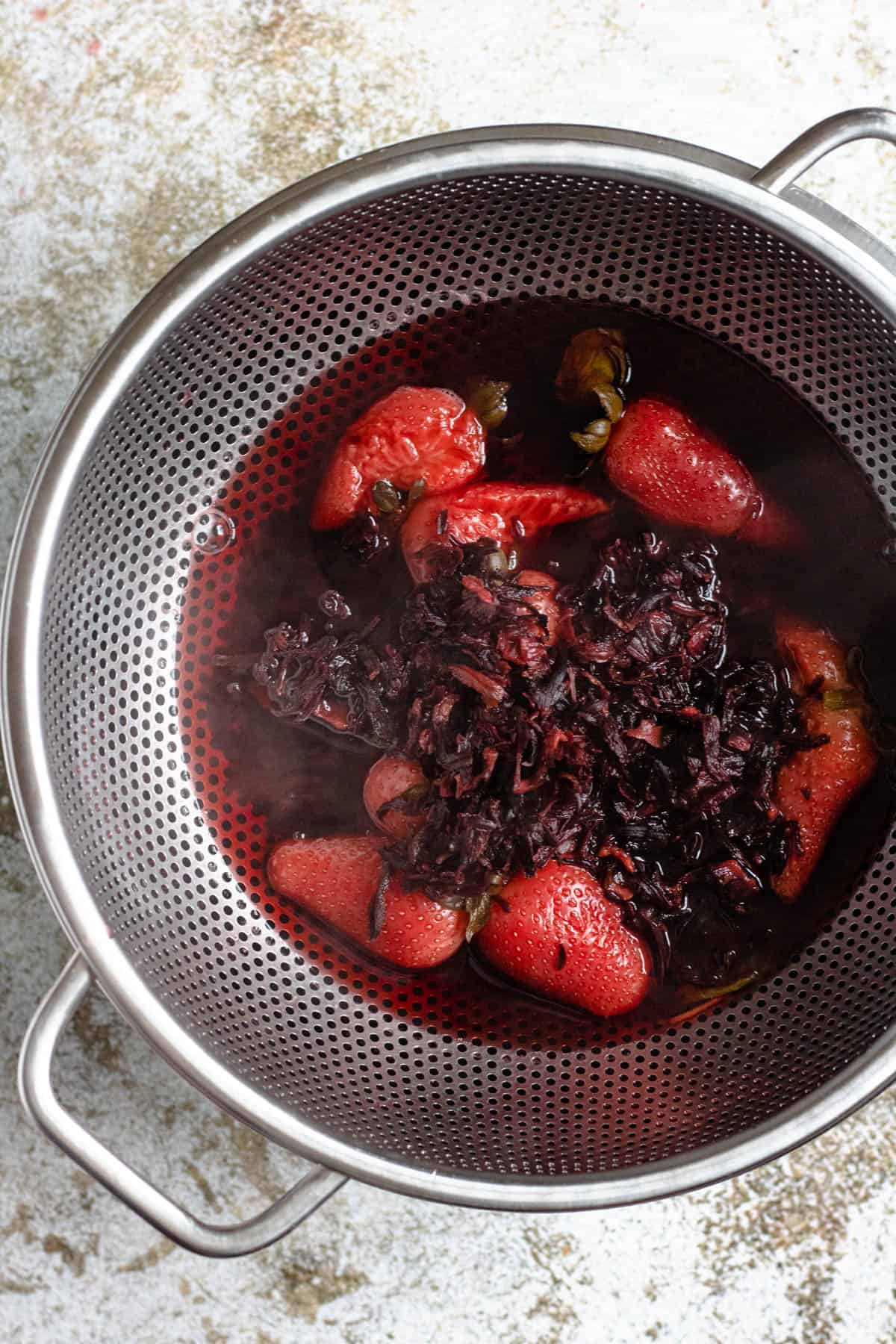 Dried hibiscus flowers and strawberries strained from tea that was brewed. 