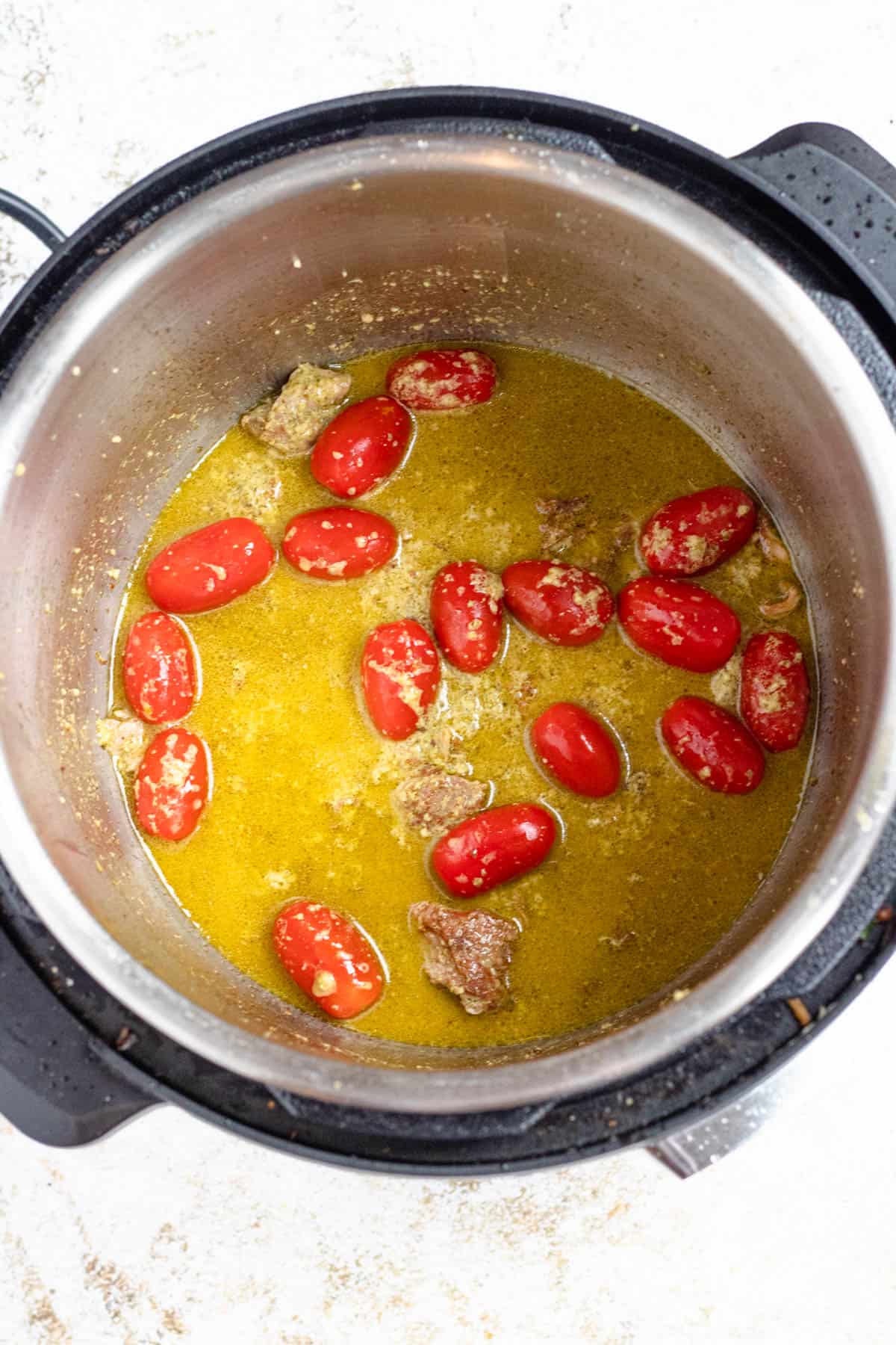 Instant pot deglazed with broth and grape tomatoes. 