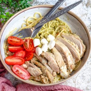 A bowl of pasta topped with pesto chicken.