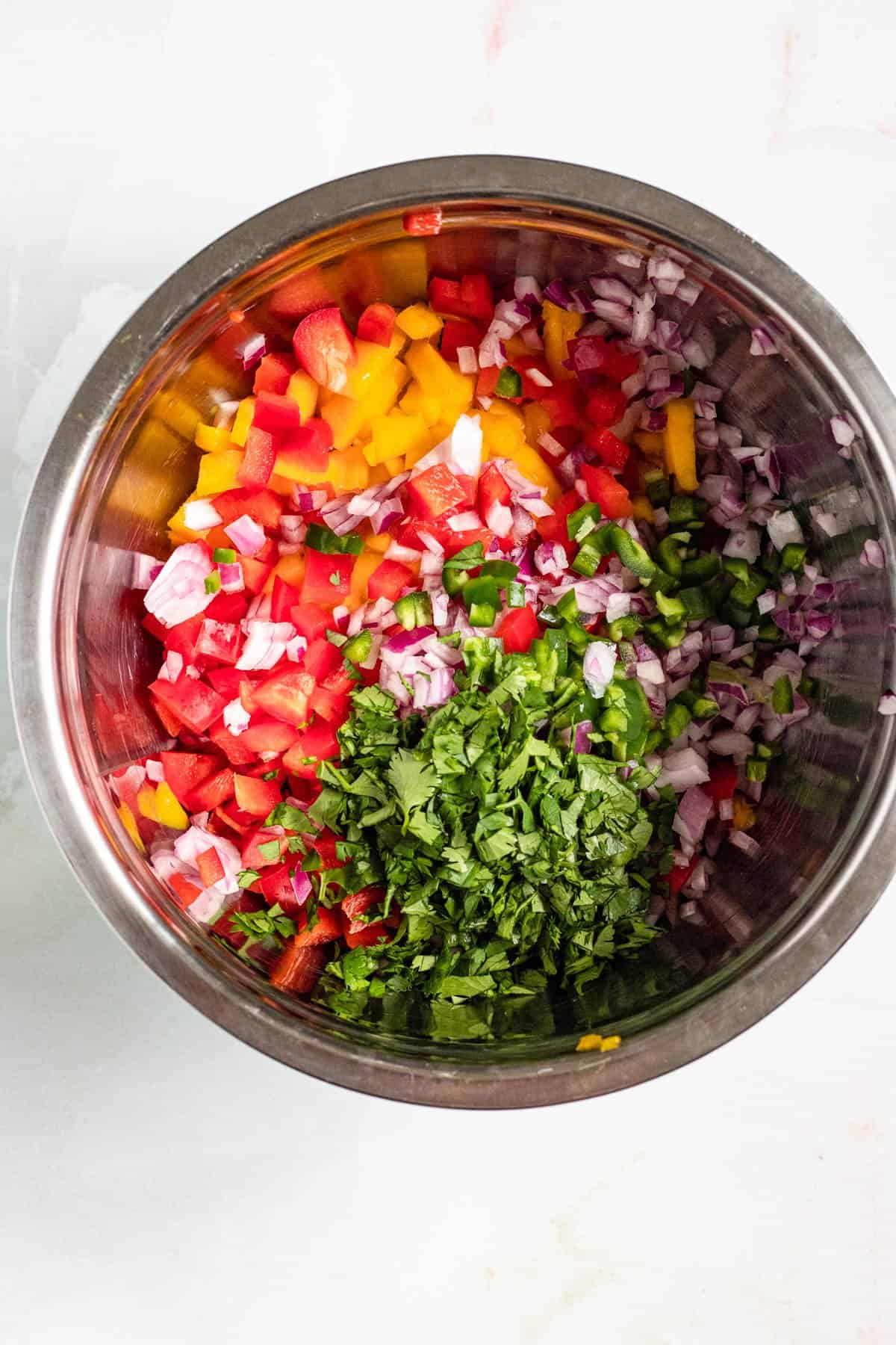 Ingredients chopped and added to a mixing bowl for mango pico de gallo. 