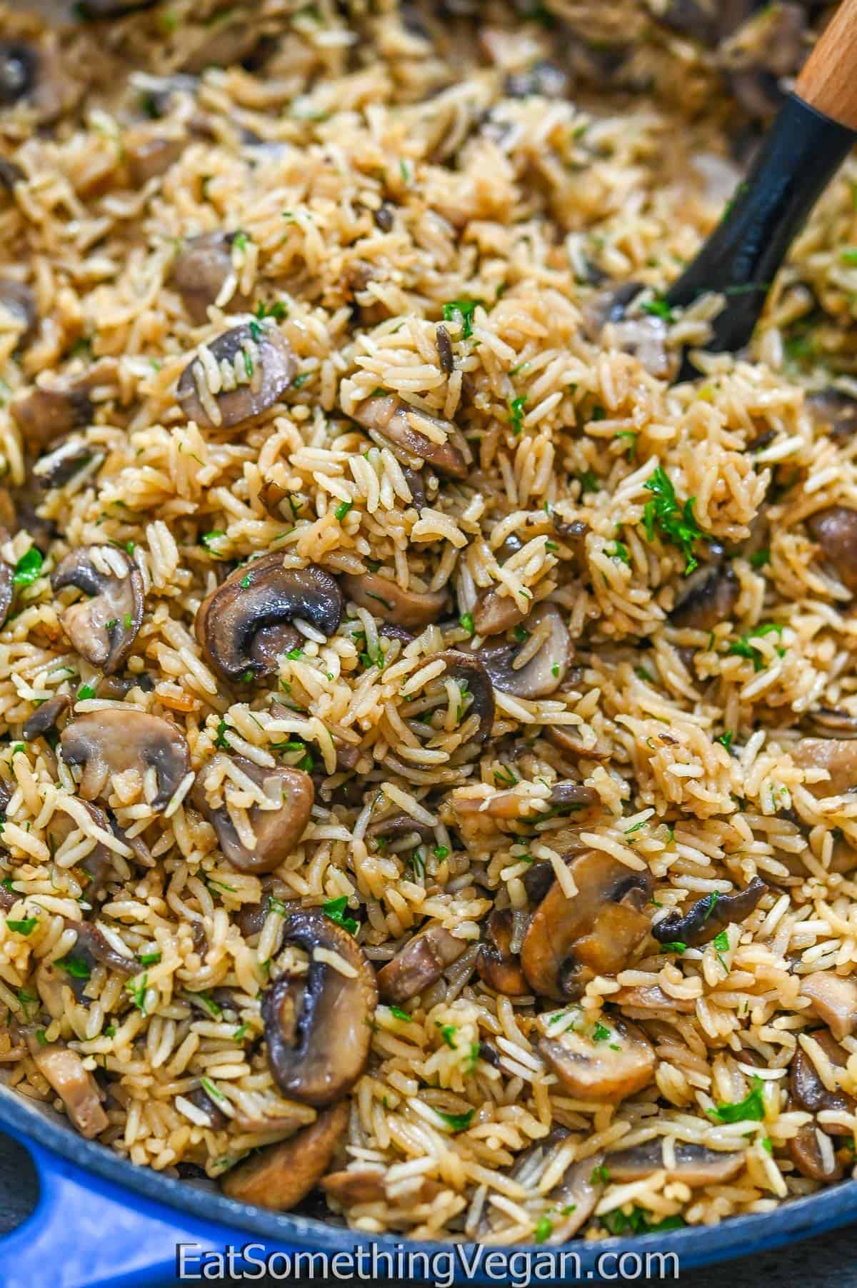 A serving spoon tucked into mushroom rice. 