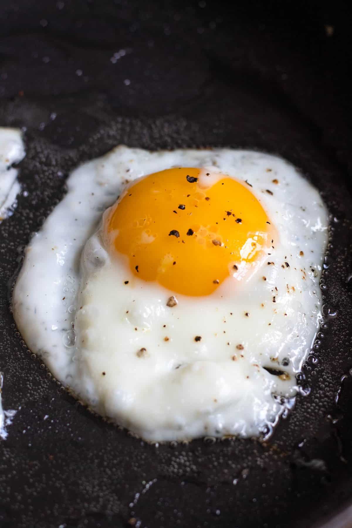 Egg being fried in a frying pan to top the Nasi Goreng. 