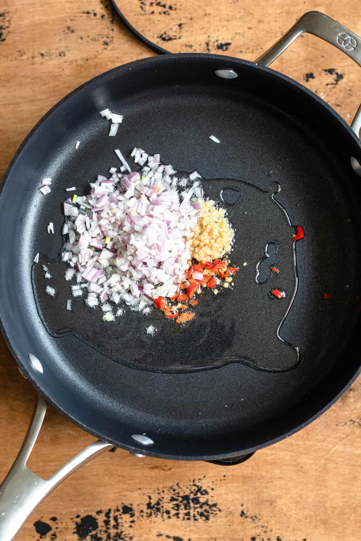 Frying pan with oil, peppers, garlic and shallots inside to start the Nasi Goreng. 