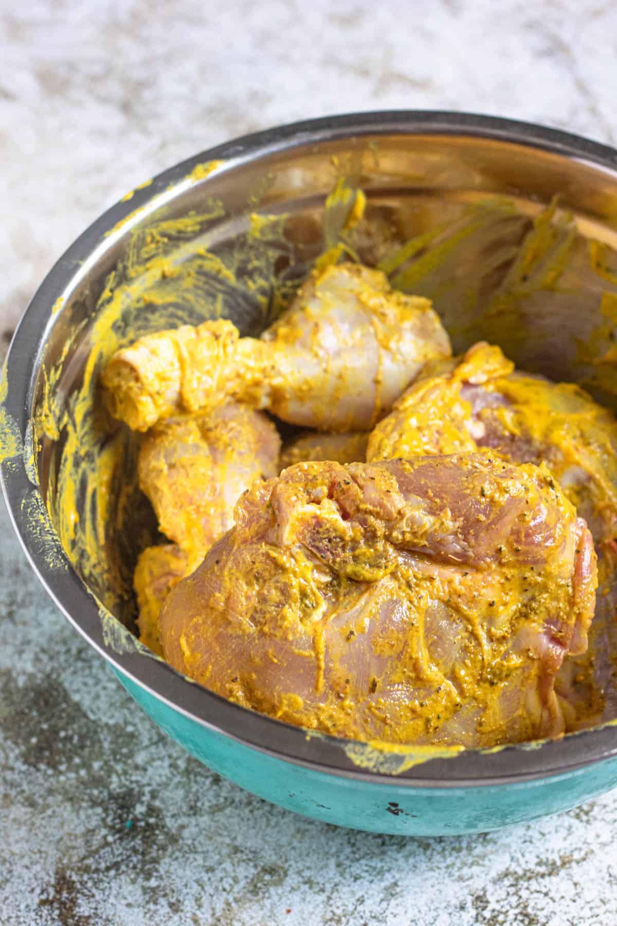 Whole raw chicken covered in a bowl combined with marinade ingredients. 