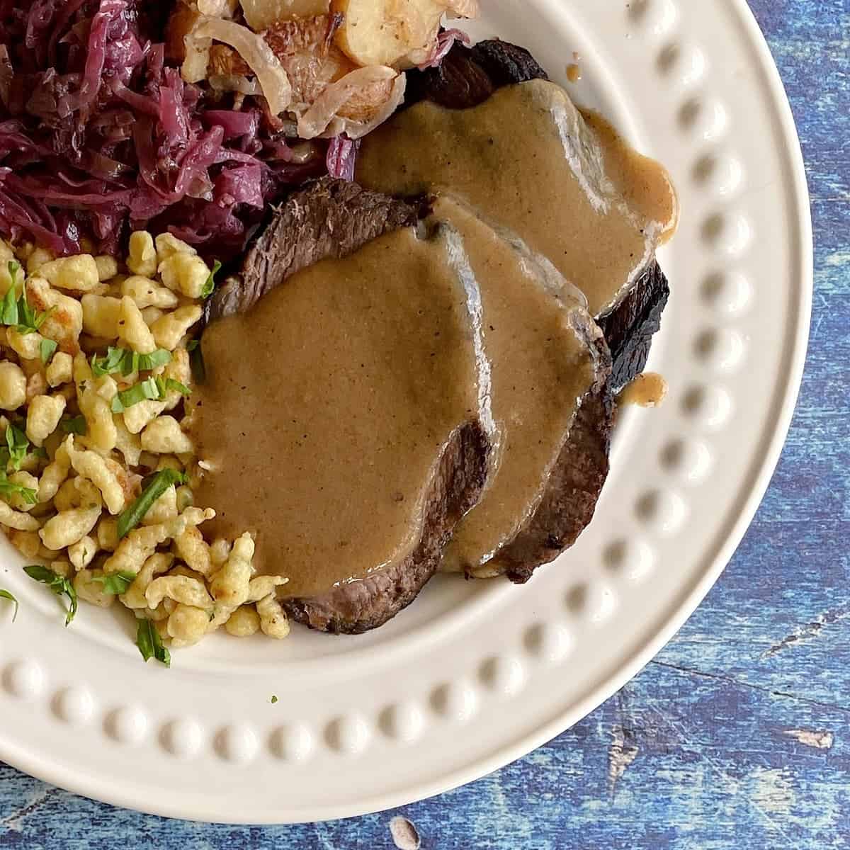 Sauerbraten on a plate with side dishes accompanying it. 