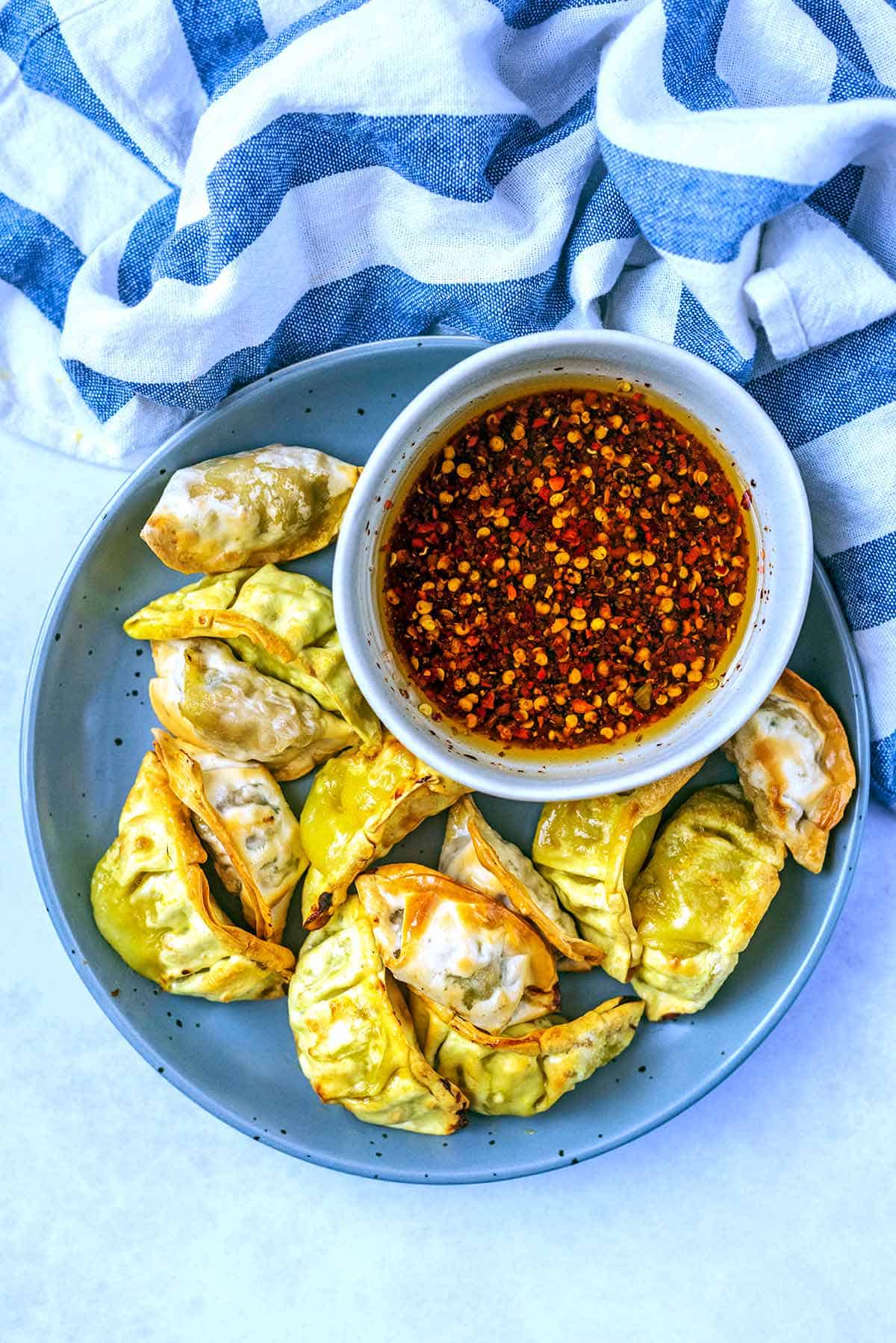 Air fryer Gyoza on a round platter with a dipping sauce. | Hungry, Healthy, Happy