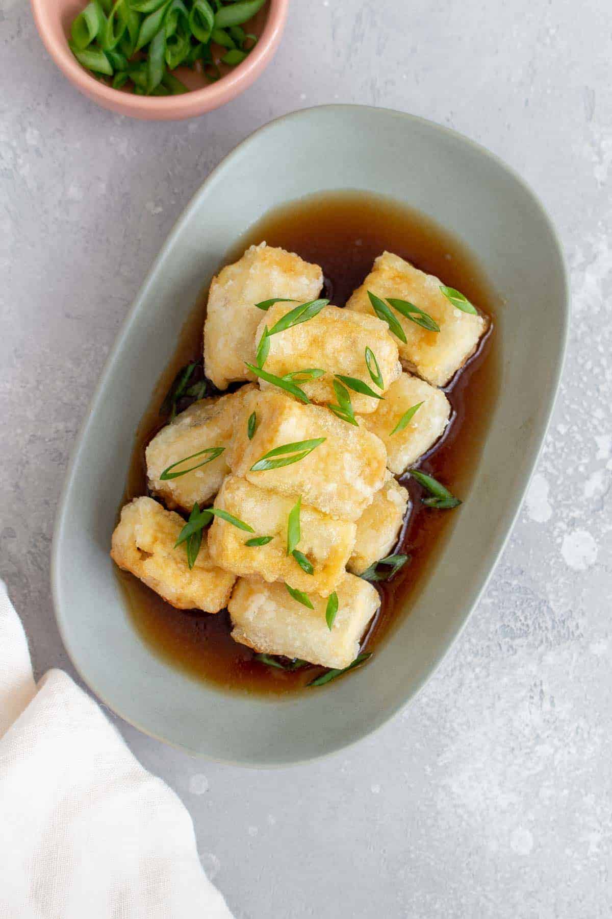 Rectangular platter of agedashi tofu with a sauce on it. | Carmy