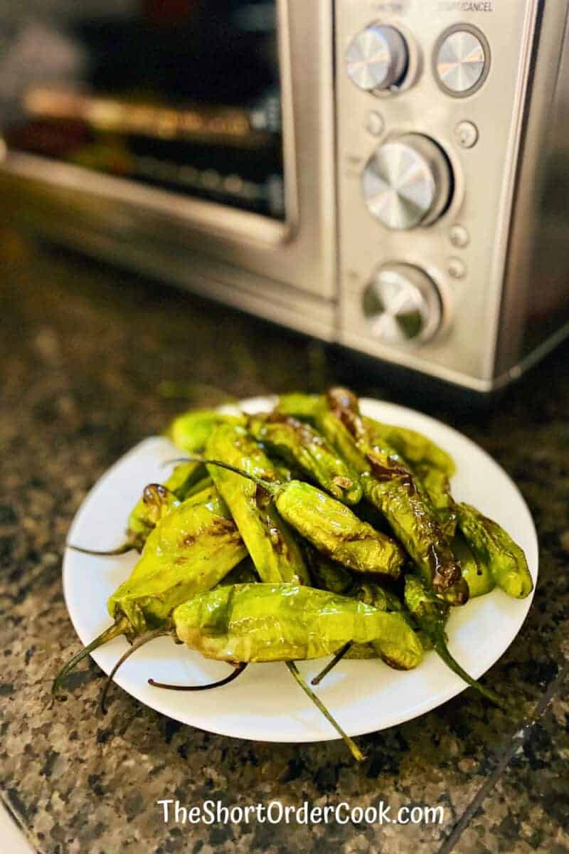 Shishito peppers on a plate in front of an air fryer. | The Short Order Cook
