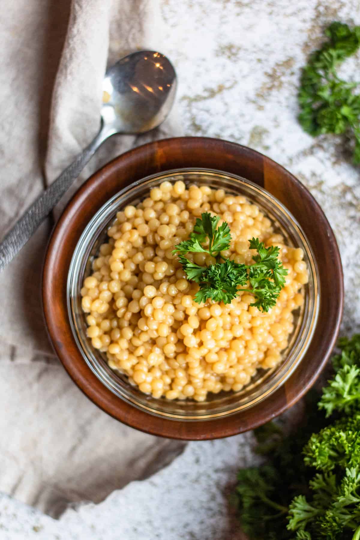 Instant Pot Israeli Couscous in a bowl with a spoon lying next to it. 