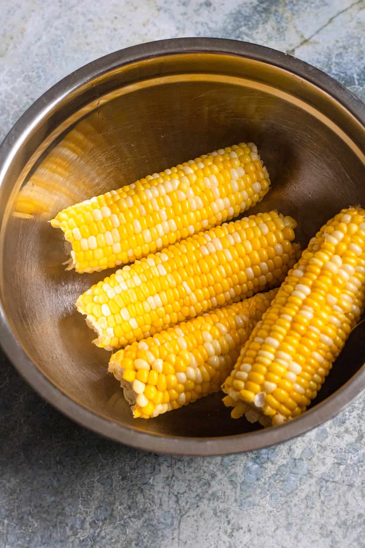 Corn on the cob sitting in a mixing bowl. 