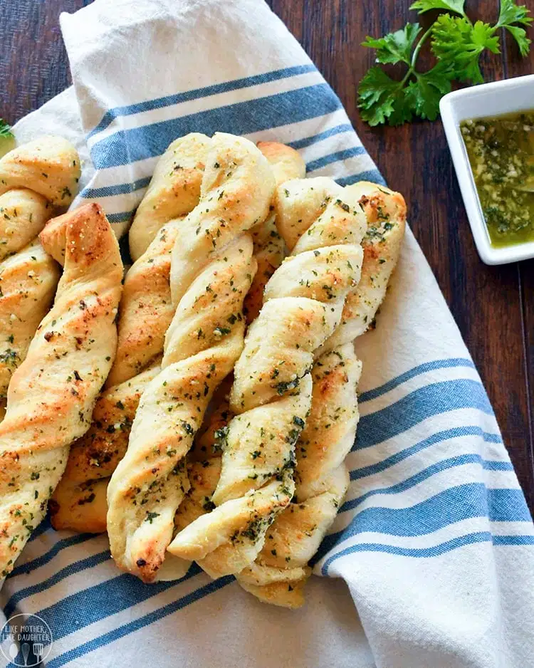 Garlic bread sticks on a blue and white towel. 