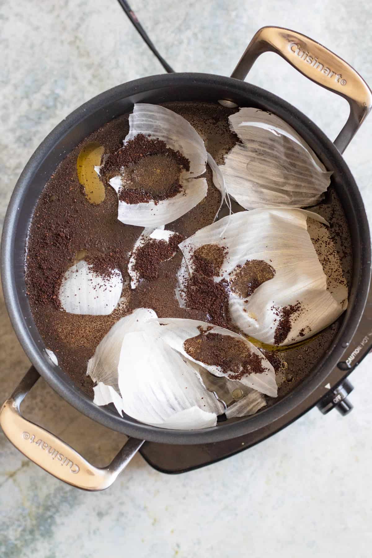 A pot filled with water, coffee grounds, and onion skins. 