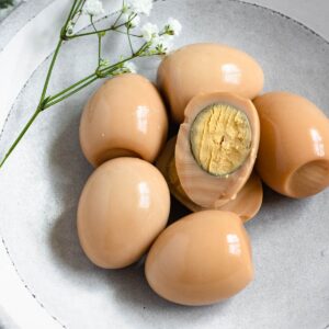 Hard boiled eggs (hamine) in a bowl with the whites dyed brown and sitting next to baby's breath flowers.