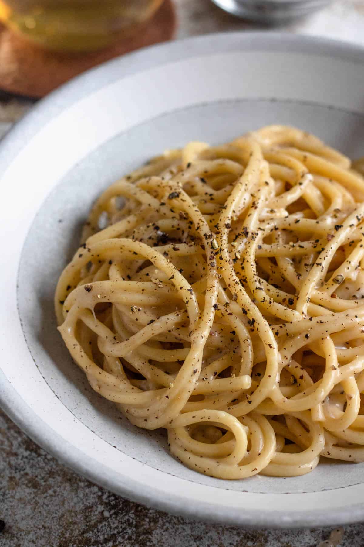 Cacio e pepe on a plate with cracked pepper over it. 