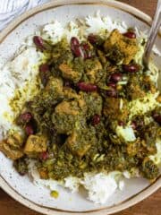 Ghormeh Sabzi served on white rice with meat, red beans, and an herb sauce.