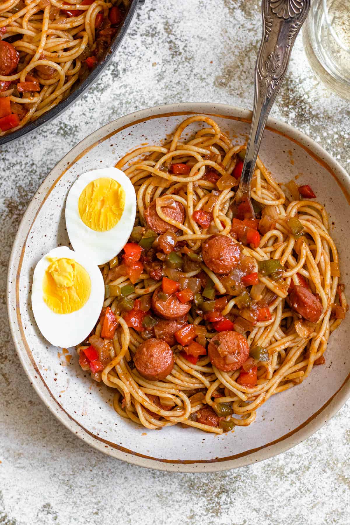 Plate of Haitian Spaghetti with a boiled egg cut in half garnished on the side. 