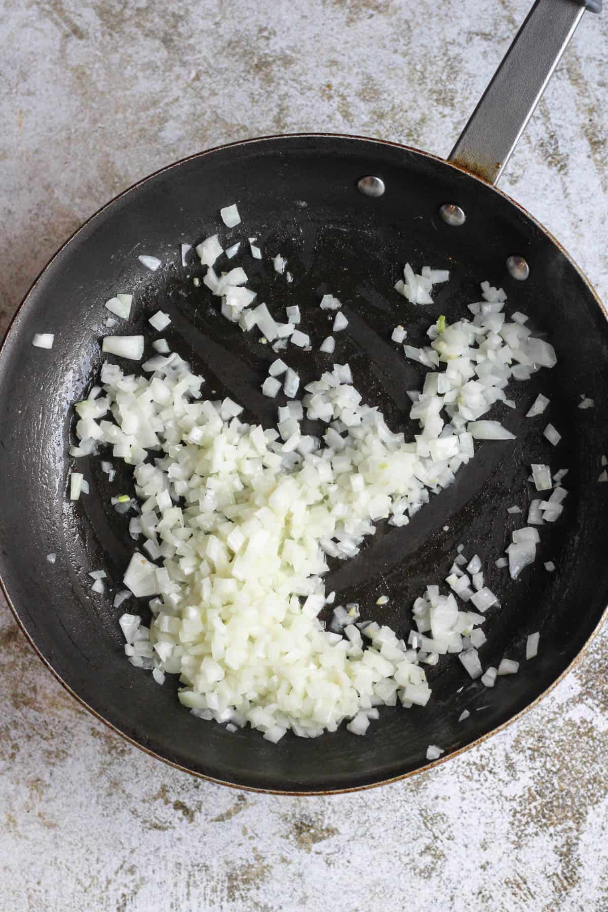 Diced onions sauteeing in a frying pan. 