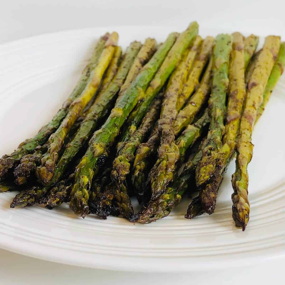Balsamic roasted asparagus served on a white serving plate. 