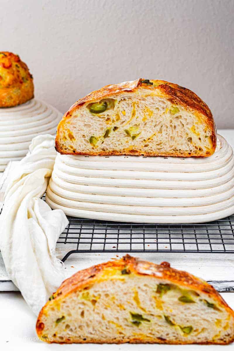 Jalapeno cheddar sourdough bread cooling on a wire rack with a slice cut off. 