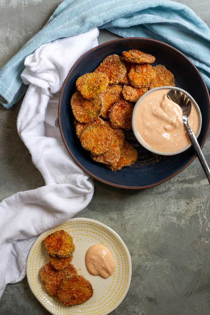 Air fried pickles on a plate with a small bowl of dipping sauce. 