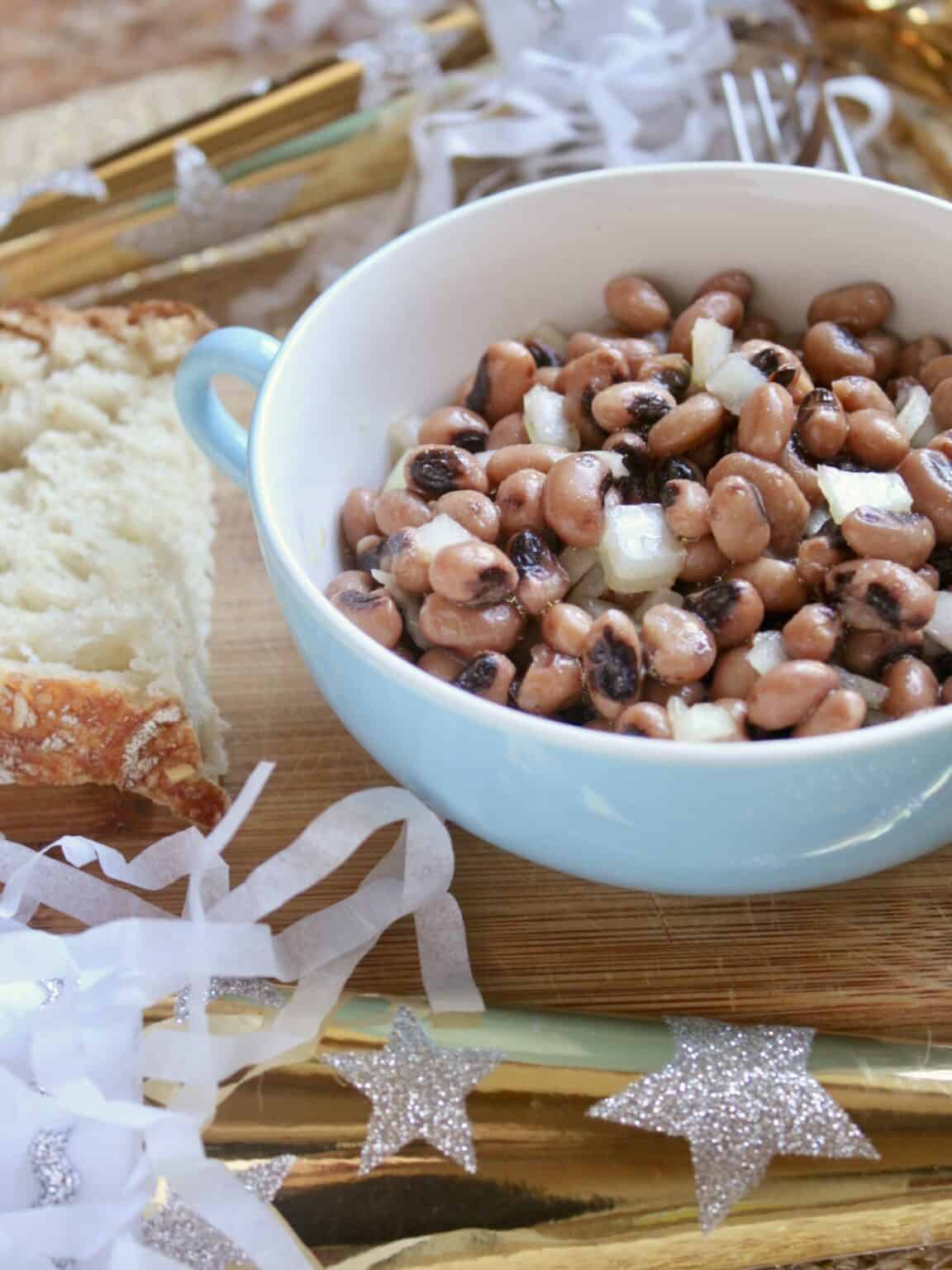 Small bowl of black eyed peas recipe with diced onions and a slice of bread next to the bowl. 