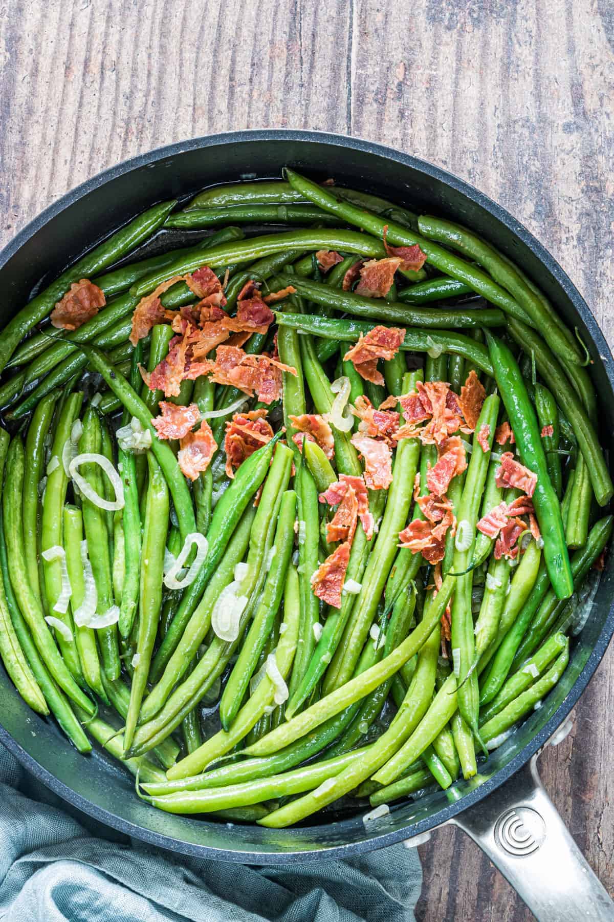 Smothered green beans in a frying pan. 