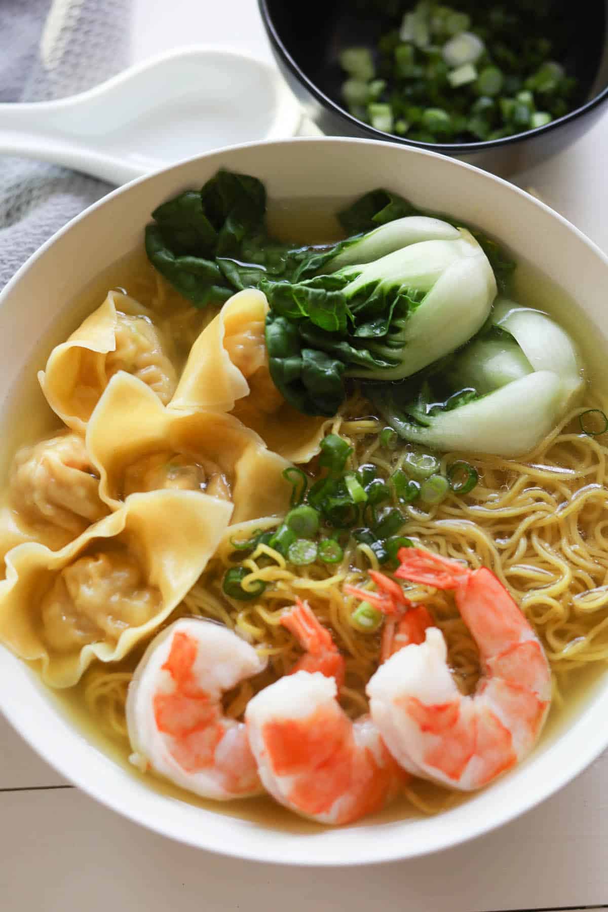 Wonton noodle soup with shrimp and veggies served in a bowl. 