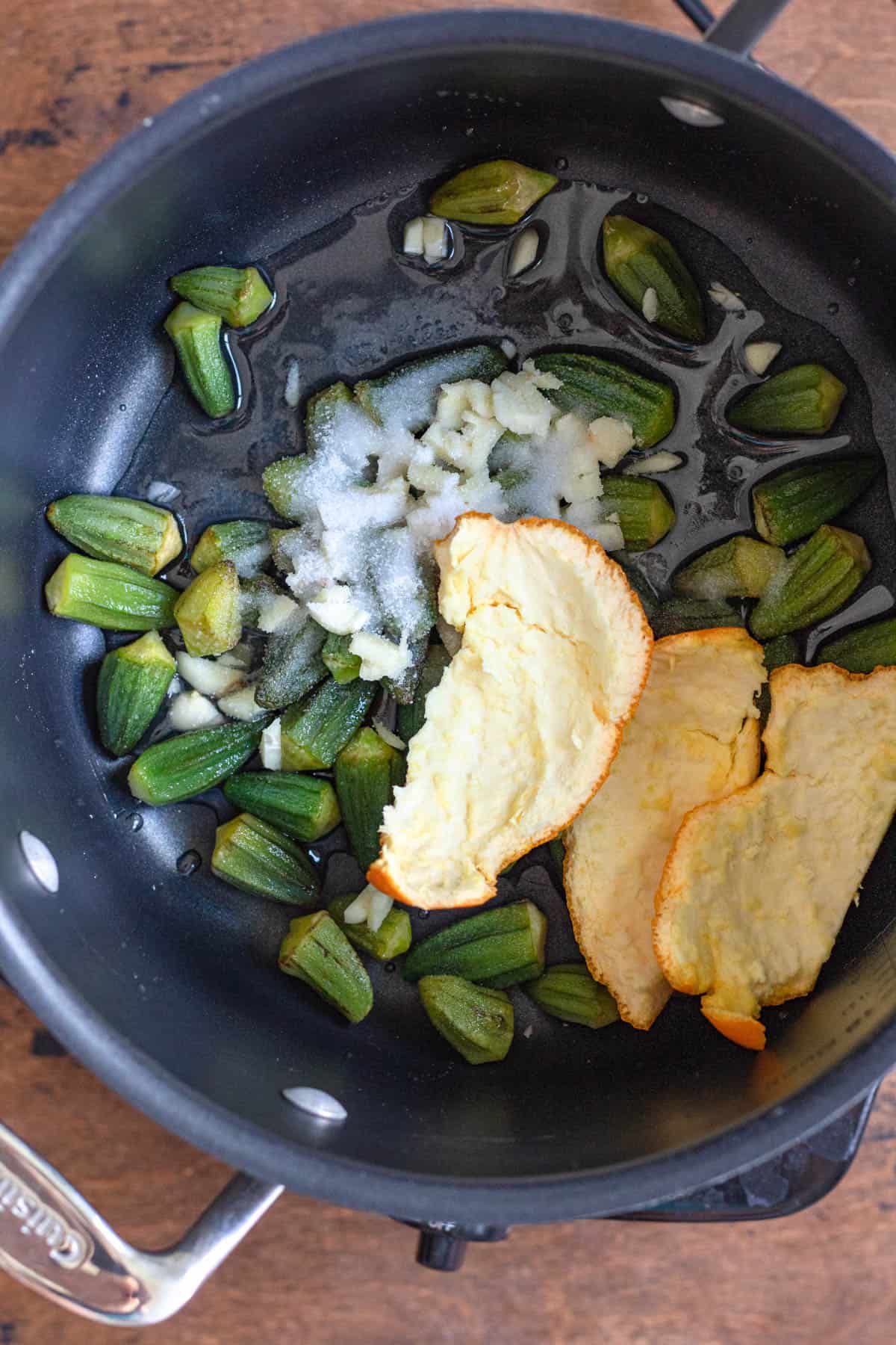 Sauce pan with okra and orange peel to start preparing Bamya recipe. 