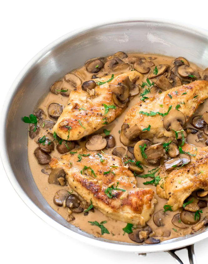 Easy chicken marsala in a skillet with sauce and mushrooms over it. 